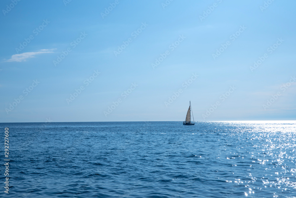 Sailing boat swimming in sea, blue sky