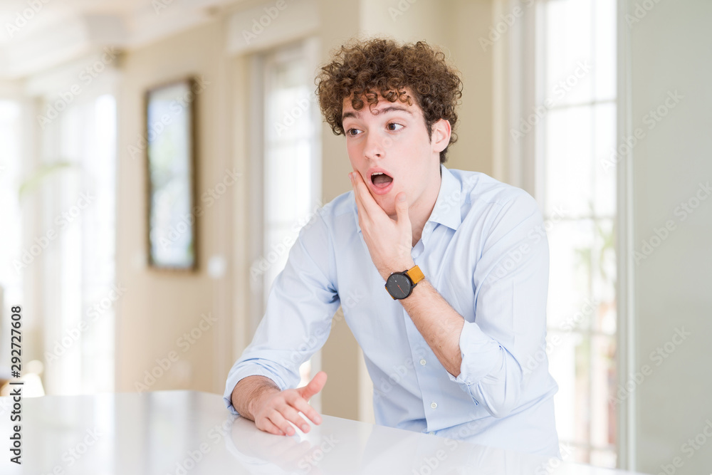 Young business man with curly read head Looking fascinated with disbelief, surprise and amazed expression with hands on chin Young business man with curly read head Looking fascinated with disbelief, surprise and amazed expression with hands on chin