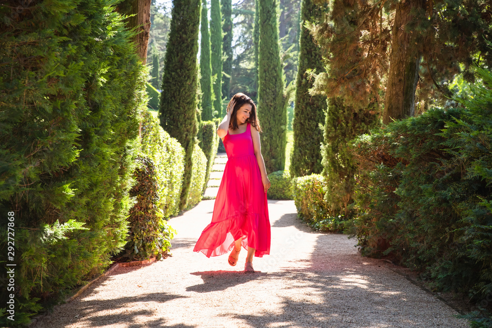 Pretty girl in red dress walking in green park Pretty girl in red dress walking in green park