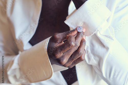 Foto Closeup photo shoot of african american man in white open shirt with diamond cufflink in hand