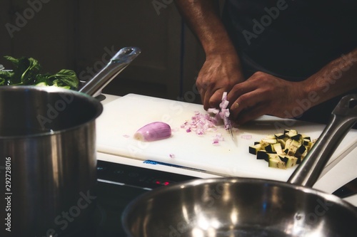 Fotografie Close up of man's hands cutting onions on a chopping board in a professional kit