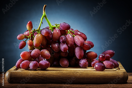 big  bunch of rose grape on wooden cutting board and black gradient background photo