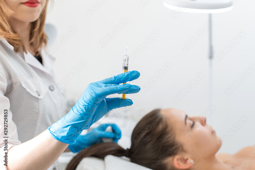 Close-up, the beautician makes injections of vitamins into the scalp for strengthening the hair. Close-up, the beautician makes injections of vitamins into the scalp for strengthening the hair.