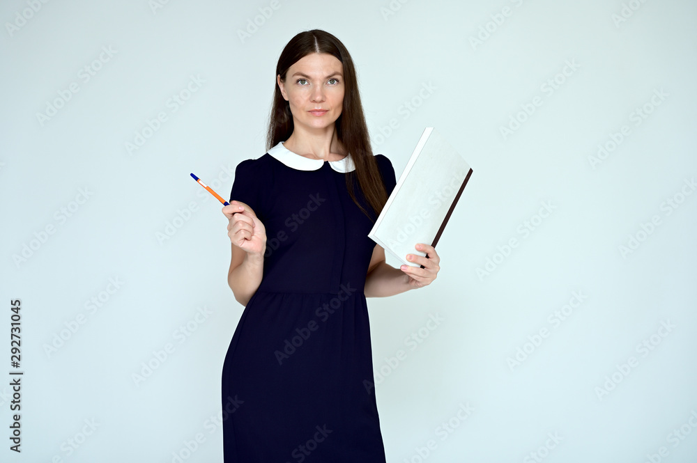 Portrait of a pretty young brunette woman with combed hair on a white background in a dark dress. He stands in different poses with a folder in his hands. Looks straight at the camera. Slim figure. Portrait of a pretty young brunette woman with combed hair on a white background in a dark dress. He stands in different poses with a folder in his hands. Looks straight at the camera. Slim figure.