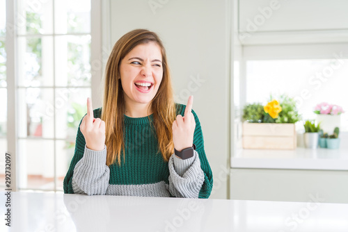 Young beautiful plus size woman wearing casual striped sweater Showing middle finger doing fuck you bad expression, provocation and rude attitude. Screaming excited © Krakenimages.com