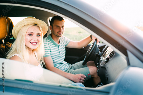 Traveling with comfort. Happy young couple enjoying road trip in their white convertible while both looking at camera and smiling