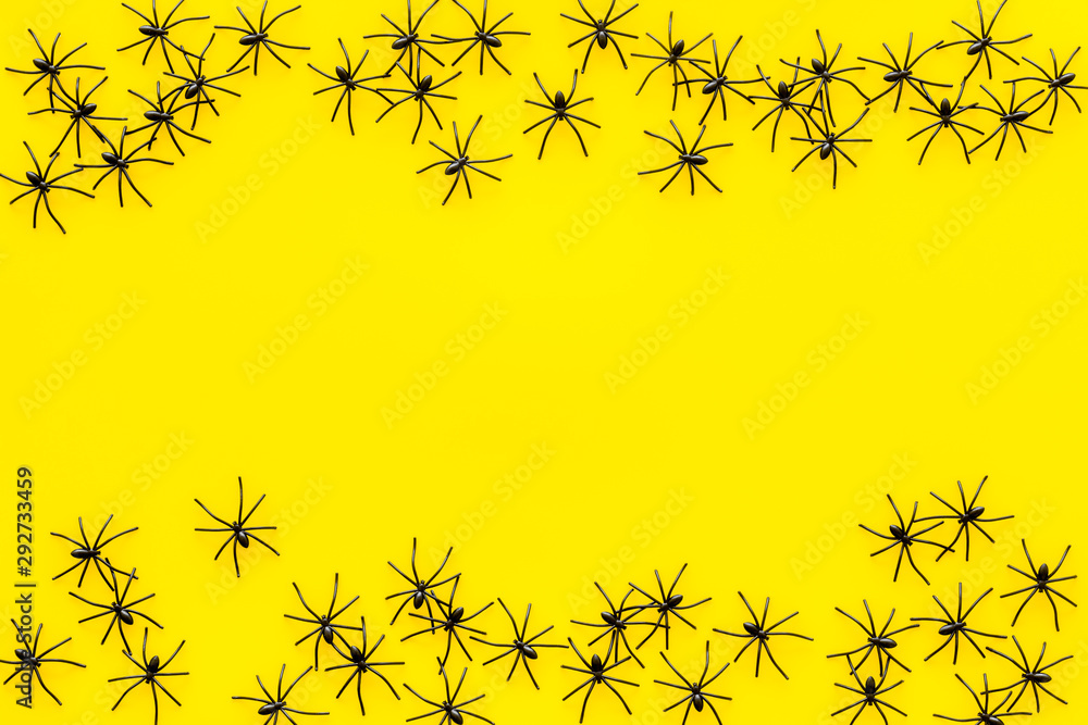 Minimalistic Halloween frame with small spiders on yellow background top view copy space