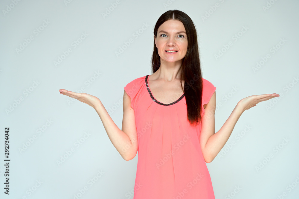 Portrait of a pretty young brunette woman with combed hair on a white background in a pink blouse. It is in different poses. Looks straight at the camera. Slim figure. Portrait of a pretty young brunette woman with combed hair on a white background in a pink blouse. It is in different poses. Looks straight at the camera. Slim figure.
