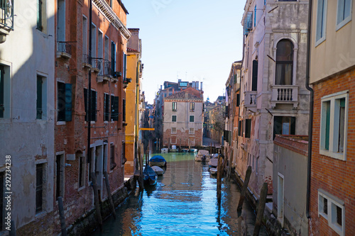 Narrow canal among old colorful brick houses in Venice  Italy.