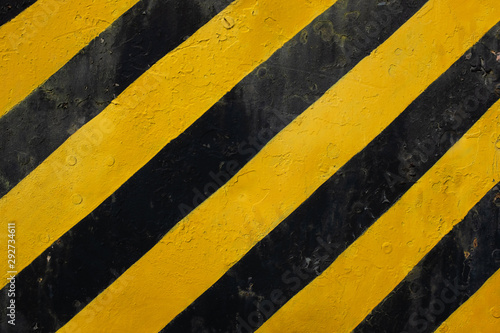 Yellow and black lines on a grunge surface means warning or caution sign © andras_csontos