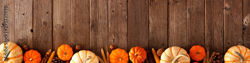Autumn bottom border banner of pumpkins and fall decor on a rustic wood background with copy space photo