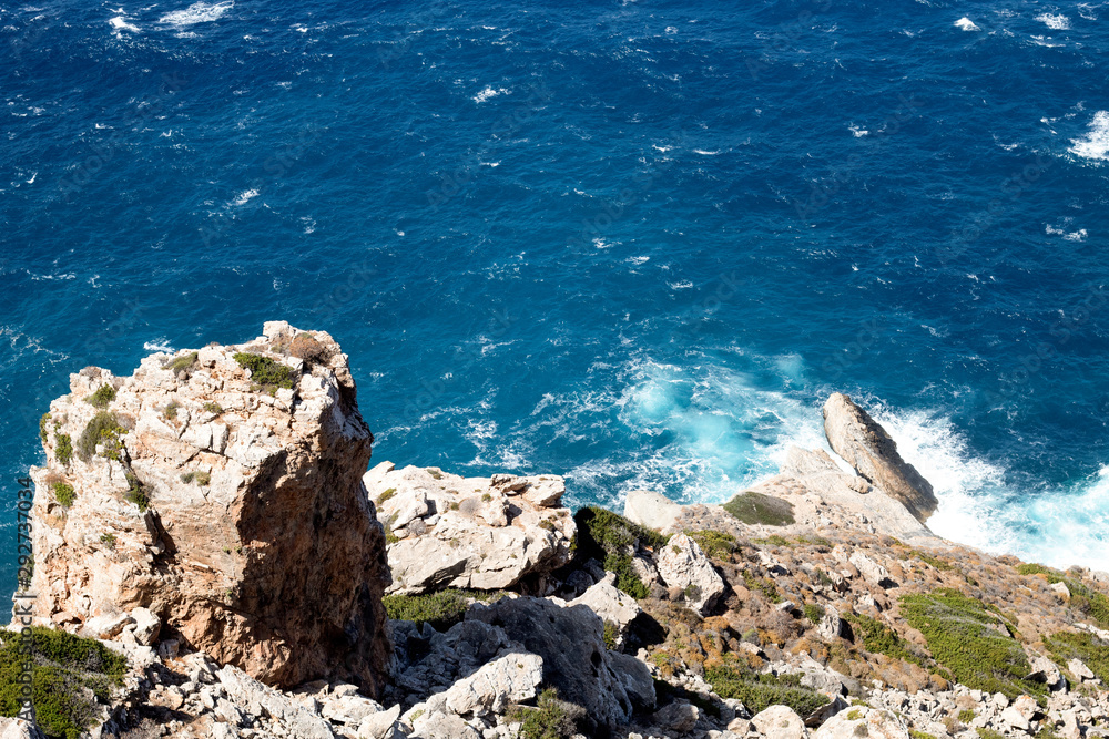 Greece, the island of Folegandros. A view to sea on a stormy and windy day from high cliffs, down to the sea.   Waves crash against the rocks. Sea spray and waves
