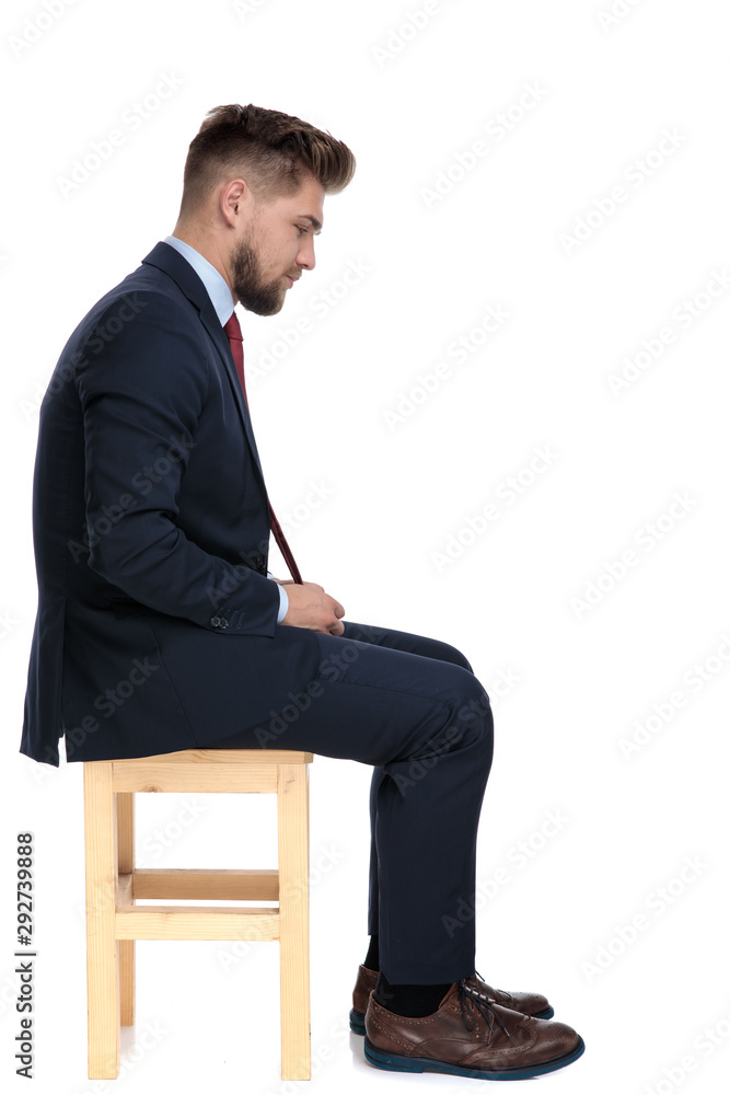 side view of young businessman sitting on wooden chair side view of young businessman sitting on wooden chair