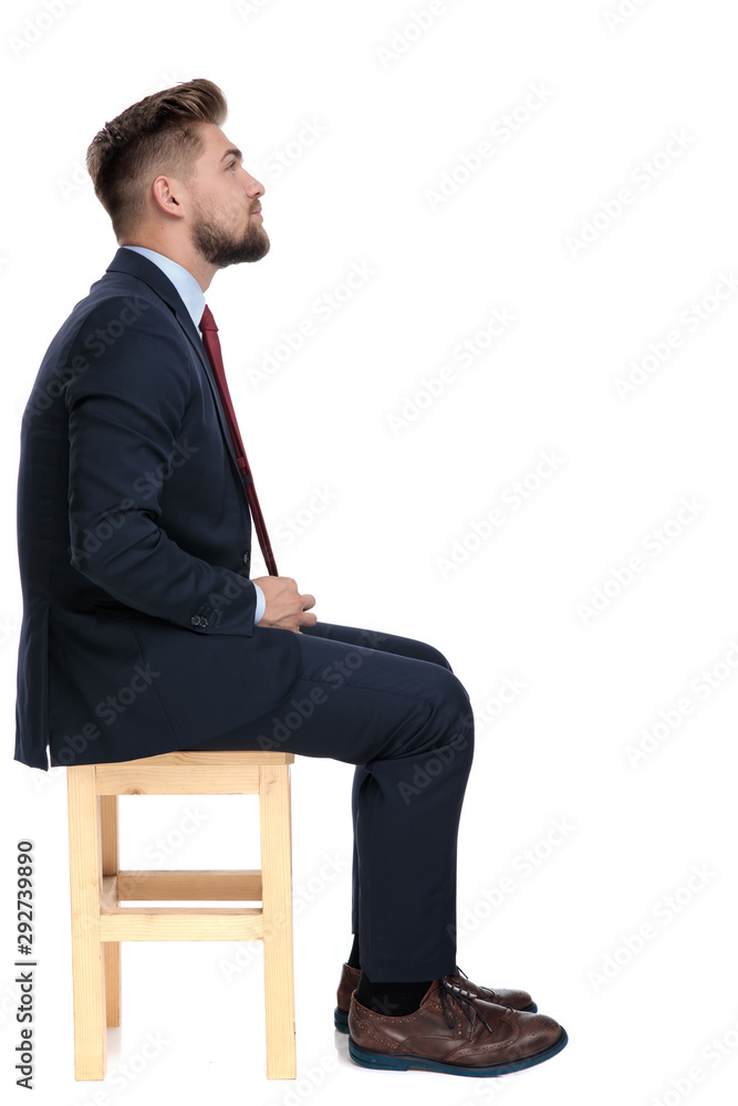 side view of young businessman fixing tie in studio side view of young businessman fixing tie in studio