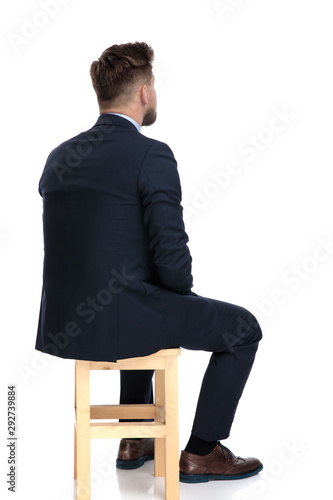Quadro su tela back view of young businessman sitting on wooden chair