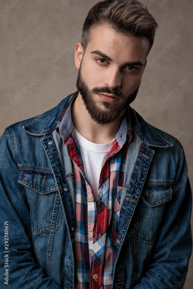 Fototapeta premium young fashion man wearing blue denim jacket on brown background