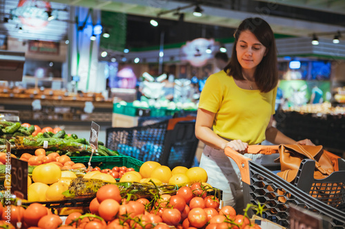 woman choosing vegetables from store shelf grocery shopping
