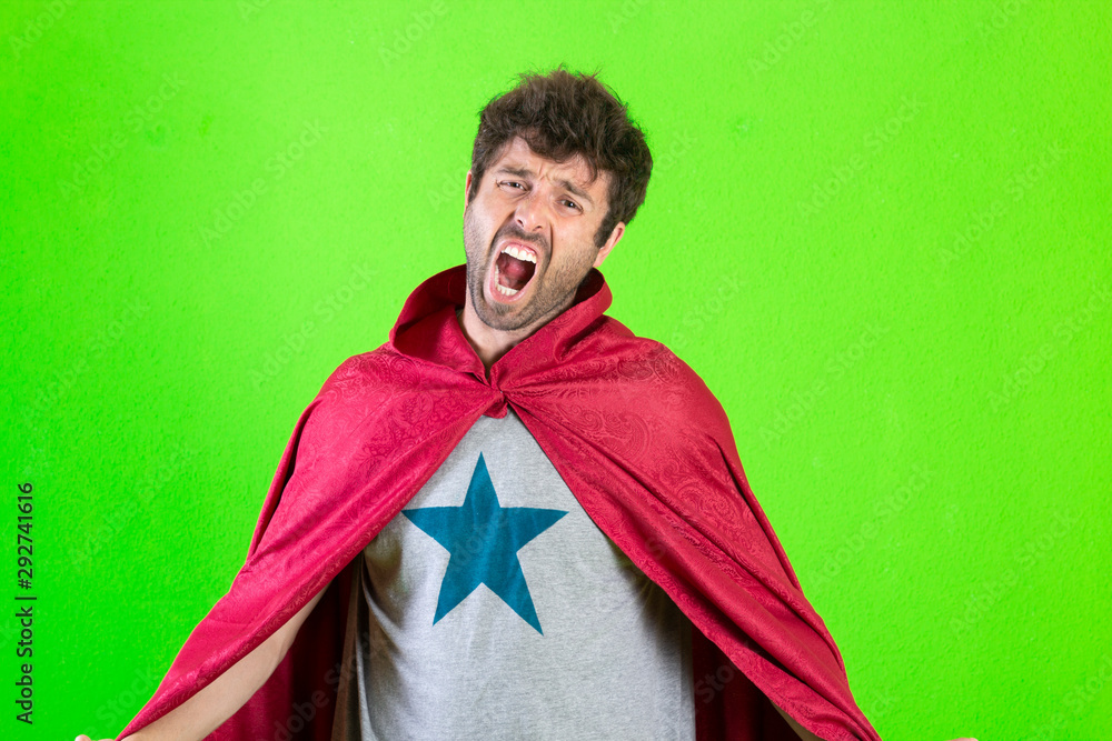 young crazy superhero man shouting, scared expression, over green background. young crazy superhero man shouting, scared expression, over green background.