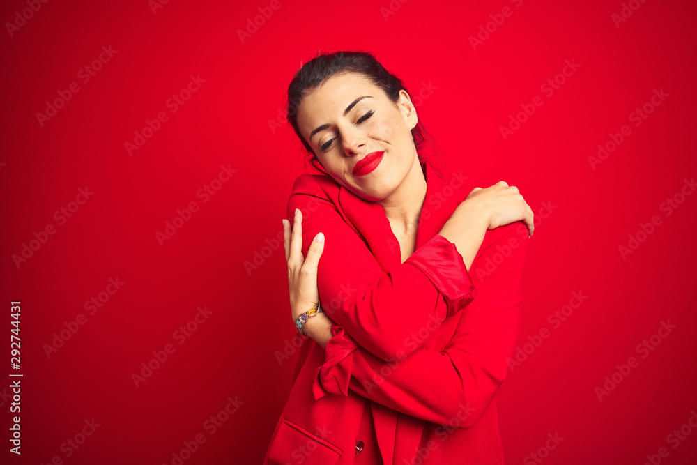 Young beautiful business woman standing over red isolated background Hugging oneself happy and positive, smiling confident. Self love and self care Young beautiful business woman standing over red isolated background Hugging oneself happy and positive, smiling confident. Self love and self care