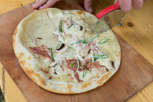 Flammkuchen beim zubereiten mit Speck, Zwiebeln und creme fresh photo