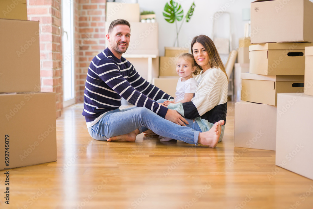 Beautiful family sitting on the floor playing with his kid at new home around cardboard boxes Beautiful family sitting on the floor playing with his kid at new home around cardboard boxes