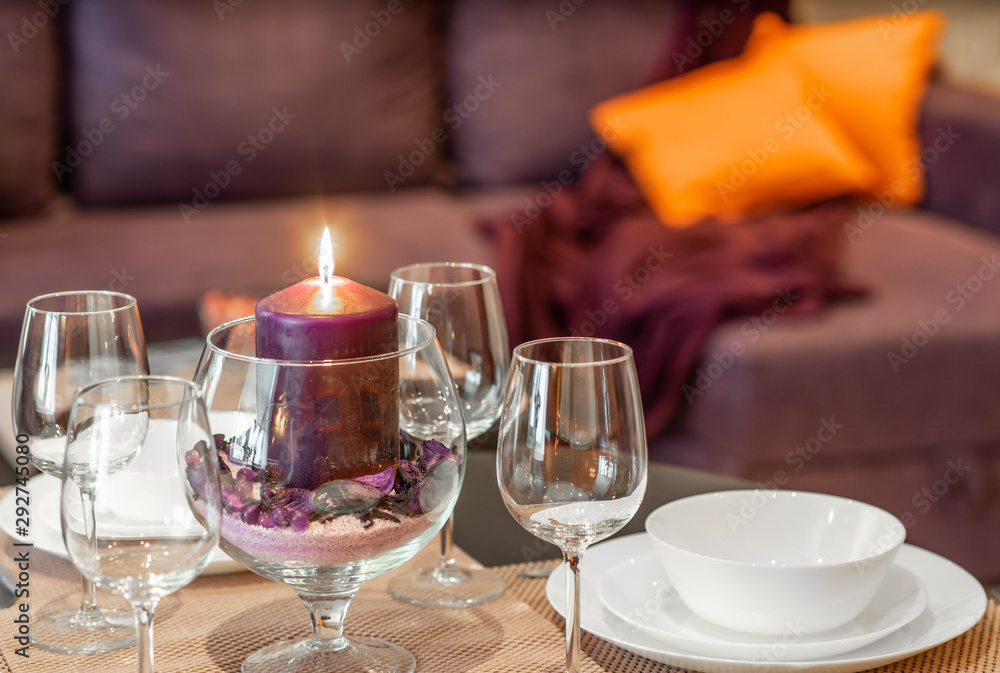 Close-up of burning candle and empty wine glasses.