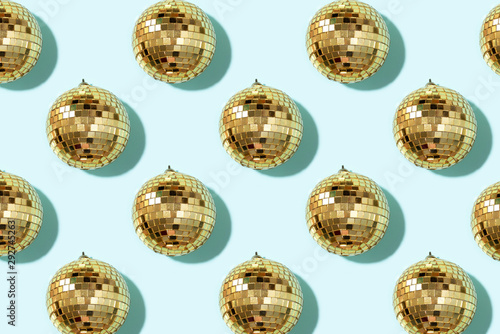 Creative Christmas pattern. Shiny gold disco balls over blue background. Flat lay, top view. New year baubles, star sparkles. Party time. Cristmas greeting card