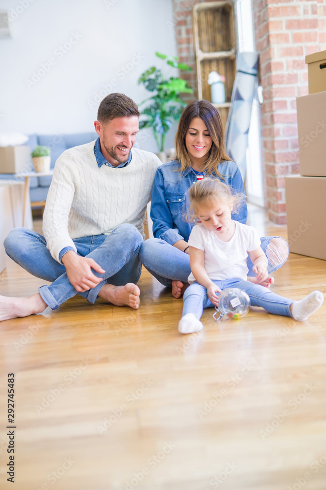 Beautiful family sitting on the floor playing with his kid at new home around cardboard boxes Beautiful family sitting on the floor playing with his kid at new home around cardboard boxes