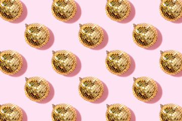 Creative Christmas pattern. Shiny gold disco balls over pink background. Flat lay, top view. New year baubles, star sparkles. Party time. Cristmas greeting card
