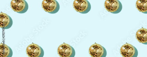 Creative Christmas pattern. Frame with shiny gold disco balls over blue background. Flat lay, top view. New year baubles, star sparkles. Party time. Cristmas greeting card