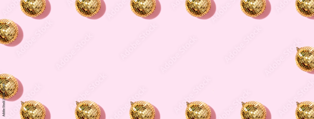 Creative Christmas pattern. Frame with shiny gold disco balls over pink background. Flat lay, top view. New year baubles, star sparkles. Party time. Cristmas greeting card