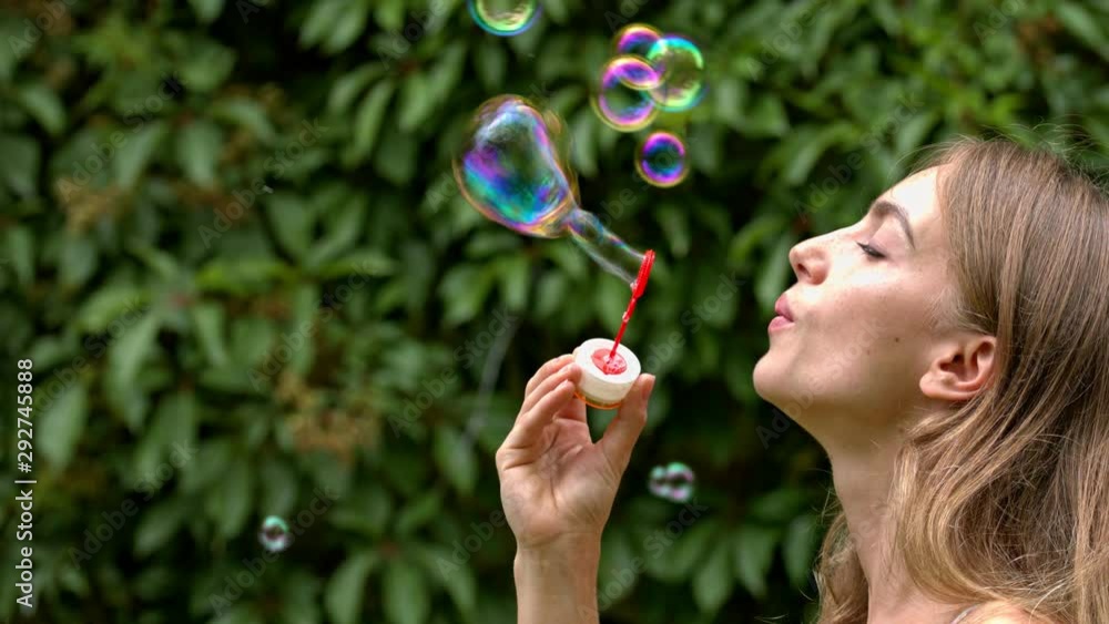 Young happy girl makes soap bubbles outdoors. Close Up Young happy girl makes soap bubbles outdoors. Close Up