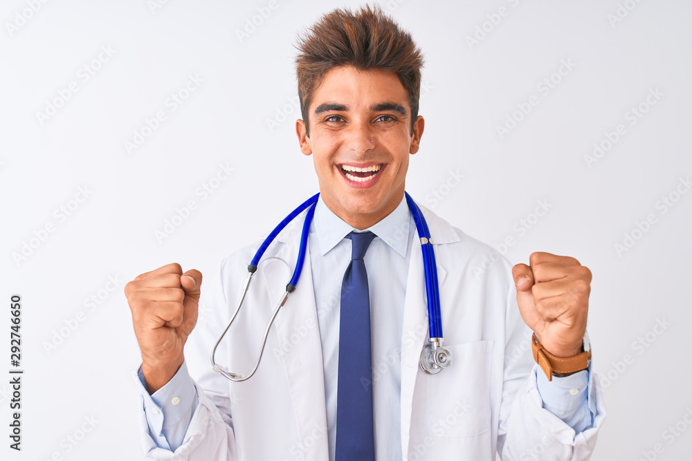 Young handsome doctor man wearing stethoscope over isolated white background celebrating surprised and amazed for success with arms raised and open eyes. Winner concept. Young handsome doctor man wearing stethoscope over isolated white background celebrating surprised and amazed for success with arms raised and open eyes. Winner concept.