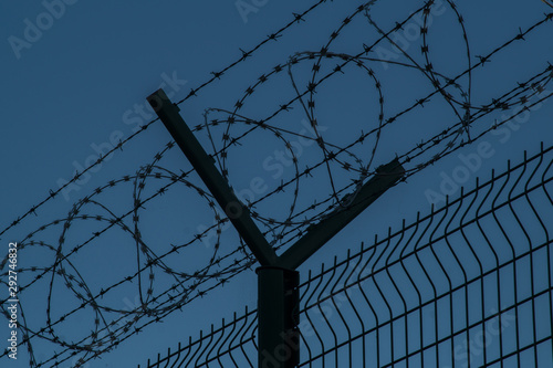 Barbed wire steel fence against the immigrants in europe. Restricted area at night.