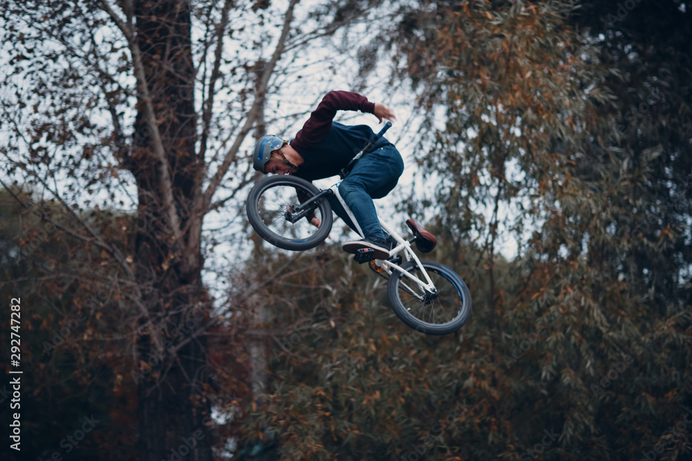 Professional young sportsman cyclist with bmx bike doing trick at skatepark Professional young sportsman cyclist with bmx bike doing trick at skatepark