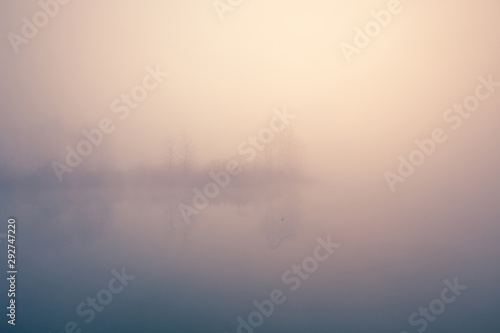 Beautiful foggy morning. Lake coast. Fog over autumn lake water.