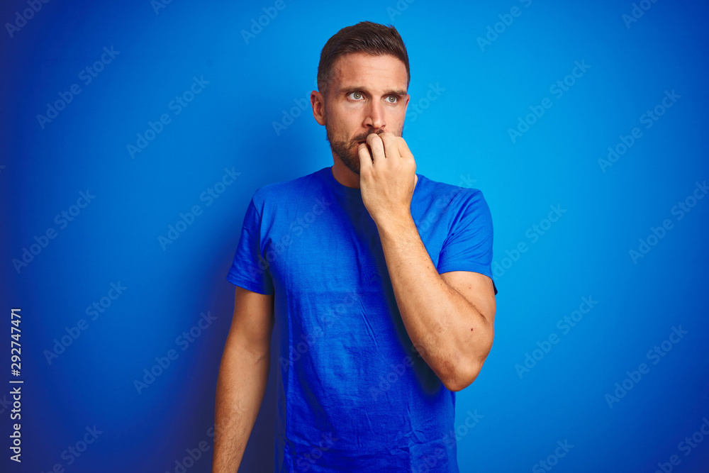 Young handsome man wearing casual t-shirt over blue isolated background looking stressed and nervous with hands on mouth biting nails. Anxiety problem. Young handsome man wearing casual t-shirt over blue isolated background looking stressed and nervous with hands on mouth biting nails. Anxiety problem.