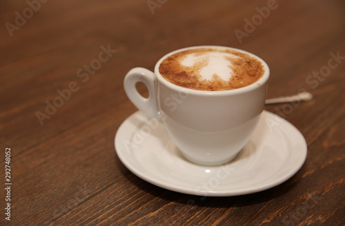 cup of cappuccino coffee on a brown wooden table. Favorite Morning drink breakfast. With copy space for text.