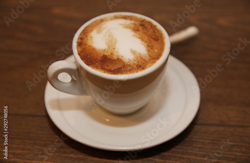 cup of cappuccino coffee on a brown wooden table. Morning drink breakfast. © Irina Tarzian