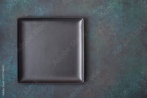 Black square plate on dark background. Top view, with copy space photo