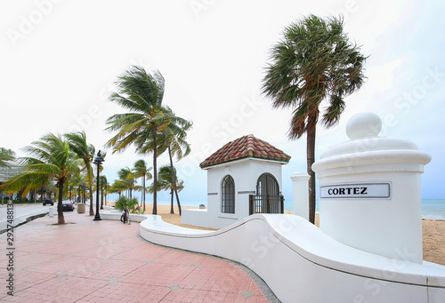 Palm trees sway as the wind blows at the wave wall Cortez Street beach entrance on A1A in Fort Lauderdale Beach, Florida, USA. photo