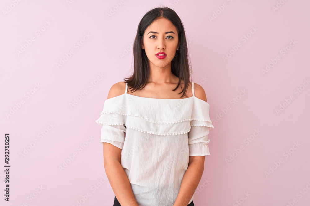 Beautiful chinese woman wearing white t-shirt standing over isolated pink background Relaxed with serious expression on face. Simple and natural looking at the camera. Beautiful chinese woman wearing white t-shirt standing over isolated pink background Relaxed with serious expression on face. Simple and natural looking at the camera.