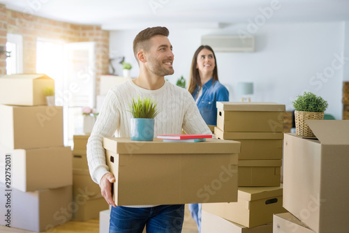 Young couple moving to a new home, smiling happy holding cardboard boxes at new apartment © Krakenimages.com