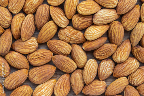 Background in the form of unshell almonds on a brown wooden background photo