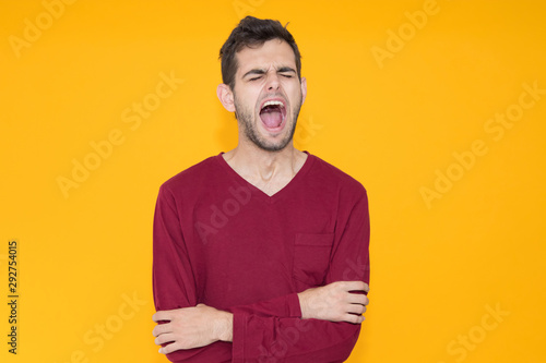 young man yawning with sleep isolated on color background