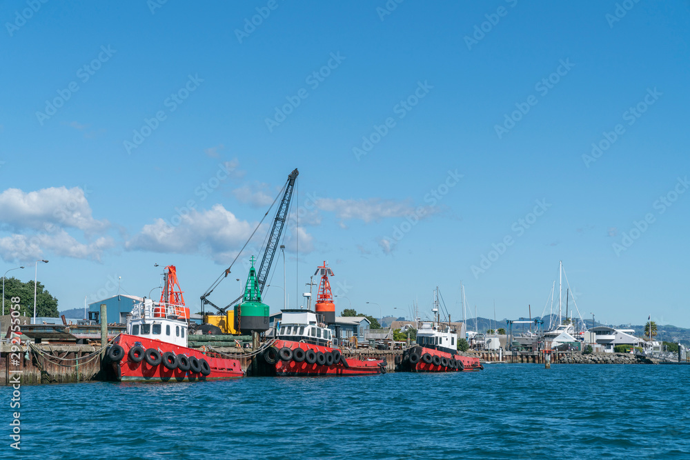 Three red harbour maintenance boats alongside dock