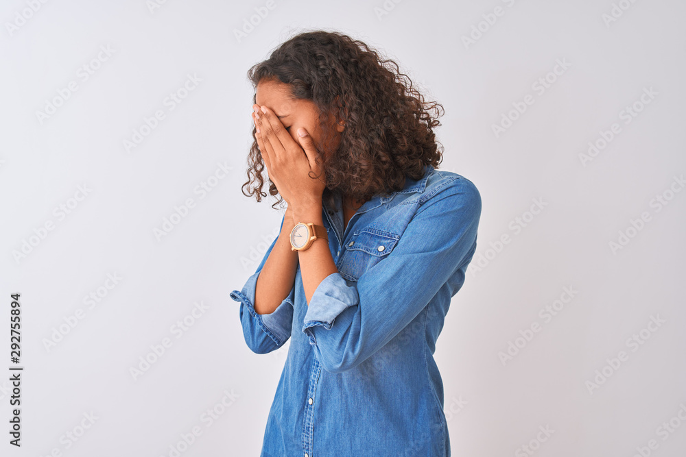 Young brazilian woman wearing denim shirt standing over isolated white background with sad expression covering face with hands while crying. Depression concept. Young brazilian woman wearing denim shirt standing over isolated white background with sad expression covering face with hands while crying. Depression concept.