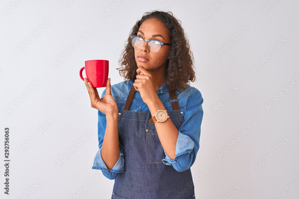 Brazilian barista woman wearing apron drinking cup of coffee over isolated white background serious face thinking about question, very confused idea Brazilian barista woman wearing apron drinking cup of coffee over isolated white background serious face thinking about question, very confused idea
