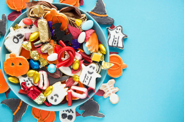 Halloween Jack o Lantern candy bowl with candy and halloween cookies Trick or Treat on blue background