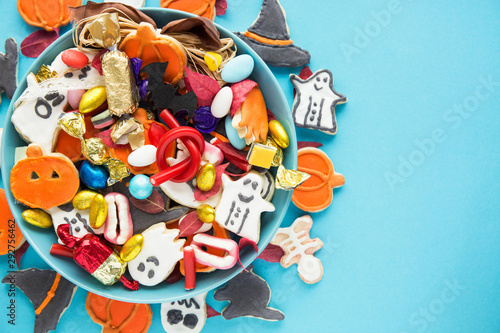 Halloween Jack o Lantern candy bowl with candy and halloween cookies Trick or Treat on blue background